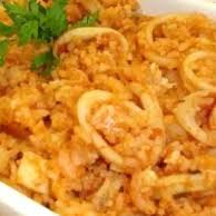 Apresento um prato de arroz preparado com camarão sete barbas, vongole, mexilhão, polvo e lula, que também é acompanhado por uma salada.