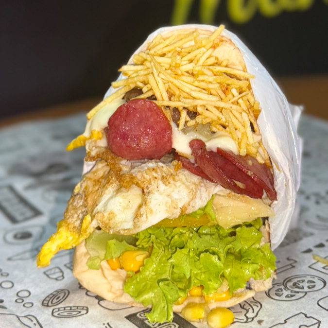 Pao, hamburguer, presunto, mussarela, calabresa, ovo, alface, tomate, milho, batata, catupiry e abacaxi.