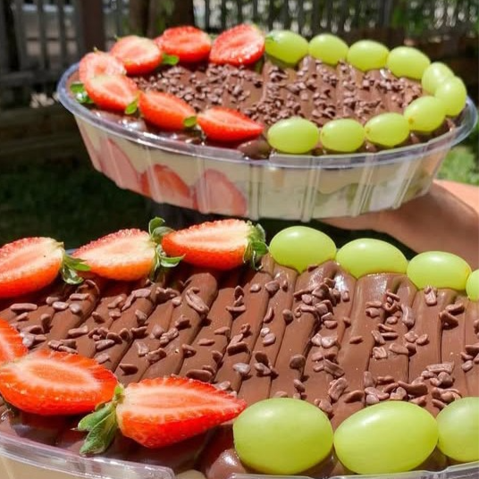 Travessa composta com camadas intercaladas de bolo de chocolate fofinho, brigadeiro cremoso de ninho, brigadeiro cremoso de chocolate, metade da travessa de uva e metade da travessa de morango. Obs: imagem da travessa de 2000ML.