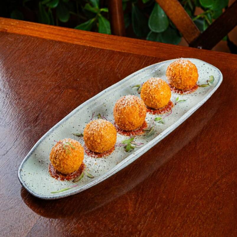 Bolinho crocantes de risoto caprese, servidos com pomodoro da casa e fios de parmesão.