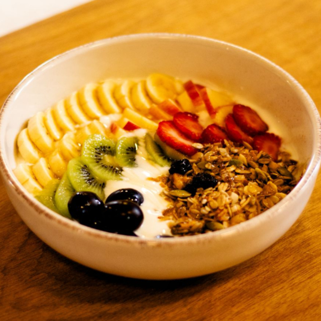 Frutas frescas do dias acompanhadas com Iogurte natural, finalizado com granola da casa e mel. Frutas variam entre: Banana, Maçã, Morango, Manga, Uva roxa e Uva verde.