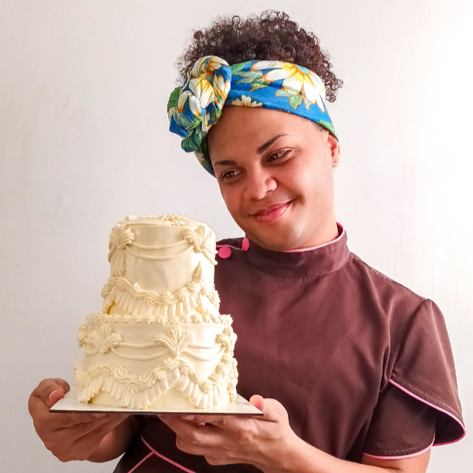 Oi, tudo bem? Eu sou Itacira, fundadora da Lobomau Doceteria! (Mas pode me chamar de Ita haha) Aqui, cada doce é feito com amor por uma equipe formada exclusivamente por pessoas trans: Somos a alma dessa confeitaria que vem adoçando Recife desde 2021. Minha jornada começou como operadora de caixa, vendendo brigadeiros nas ruas e bares da cidade. De lá pra cá, transformei minha paixão em arte: bolos cheios de personalidade, cobertos com buttercream e feitos para encantar. Em 2024, tive a honra de participar da 10ª temporada do Bake Off Brasil, um dos maiores realities de confeitaria da América Latina, um sonho realizado! Na Lobomau, cada criação é feita com carinho, dedicação e alegria, sempre com um único objetivo: adoçar seus momentos mais especiais.