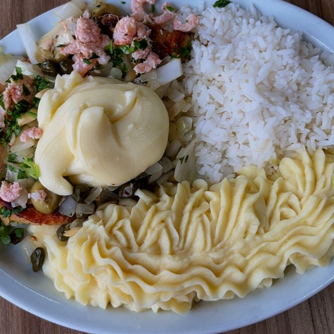Pescada grelhada, acompanha arroz, alcaparras, azeitona, cebola e camarão, e purê de batatas finalizado com catupiry gratinado.