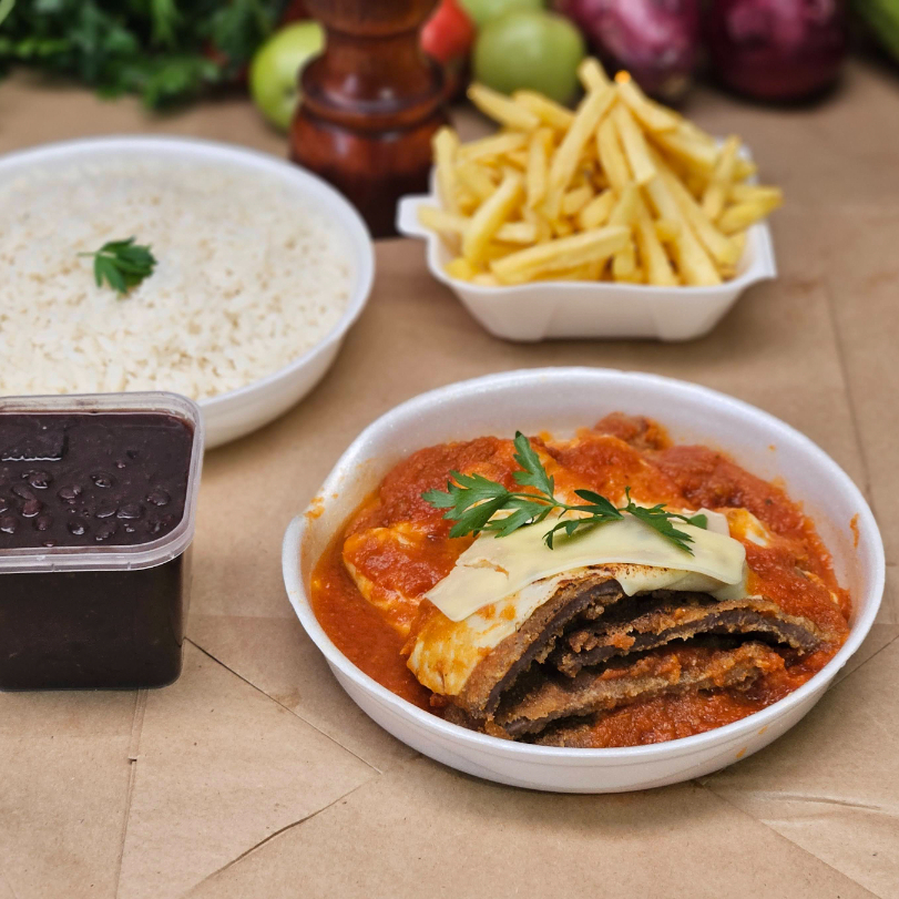 Nossa parmegiana ganha vida com um molho pomodoro artesanal, preparado no Brado Bar com tomates frescos de produtores locais e temperos naturais como salsão, salsinha e cebola. O resultado é um sabor caseiro e único, que envolve a alcatra angus empanada — crocante por fora, suculenta por dentro — e é finalizada com queijo gratinado. Acompanha: - Arroz temperado com cebola e alho (350 g) – Marmita P - Feijão do Dia (250 ml) – Potinho lacrado - Batata frita crocante (120 g) – Marmitinha H3 - Carne à Parmegiana (300 g) – Marmita M ** Serve de 1 a 2 pessoas.