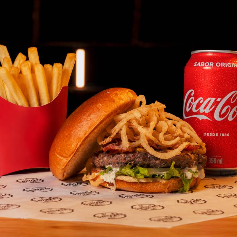 Hambúrguer artesanal 150g com queijo cheddar cremoso, bacon crocante, cebola crispy feita na casa, molho especial e pão brioche + porção de batata frita + 1 refrigerante lata.