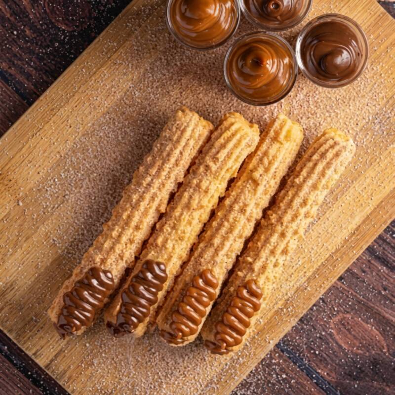 Apresentamos o nosso 'Churros Combo Tradicional Meio a Meio', composto por quatro unidades irresistíveis. Estes churros são feitos na hora para garantir a sua textura super sequinha e crocante, e são delicadamente passados numa mistura de açúcar com canela para um sabor adicional. Cada churro é recheado com capricho, apenas por dentro, resultando em um equilíbrio perfeito entre a doçura do recheio