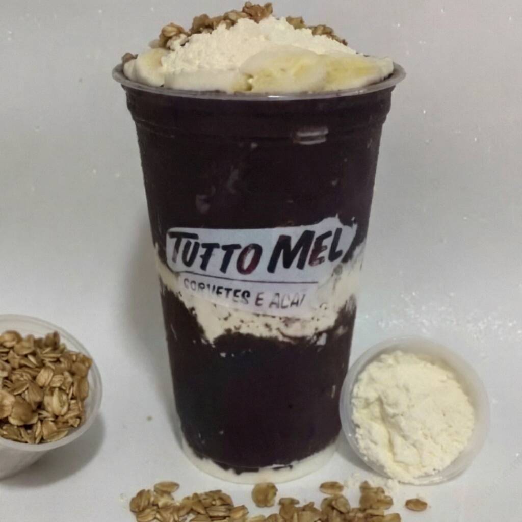 Açaí tradicional de 500 ml. Os acompanhamentos são montados em camadas: banana, granola, leite em pó e leite condensado. Não enviados separadamente.