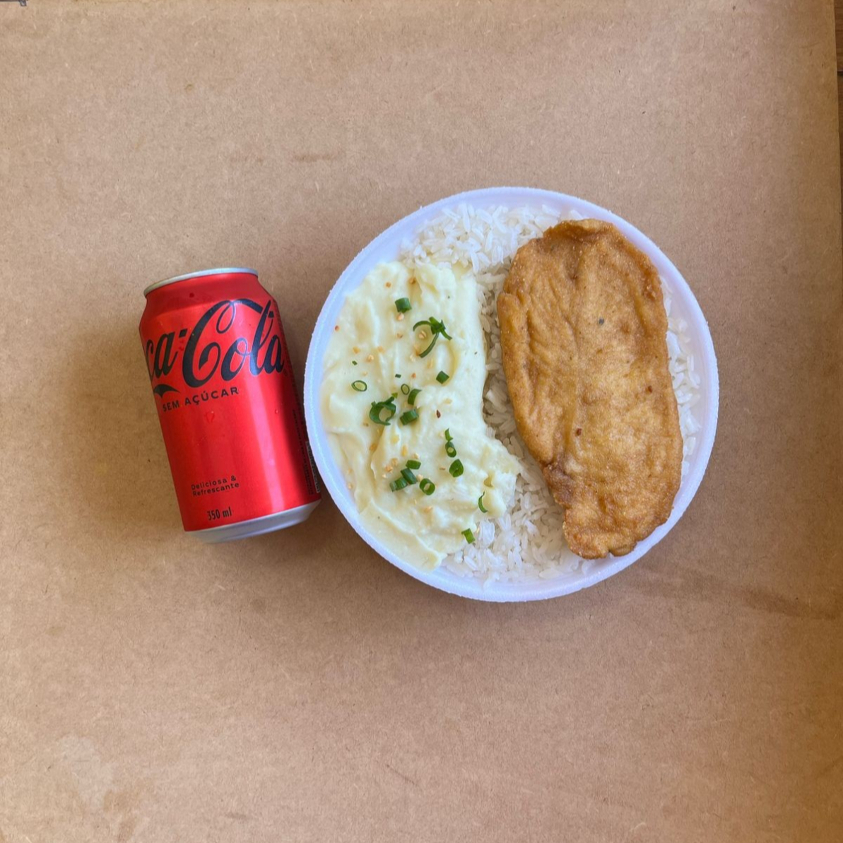 Marmita com delicioso filé de frango empanado na massa crocante acompanhado de arroz branco, feijão e purê de batatas inglesas. Acompanha refrigerante Coca Cola lata Zero sem açúcar 350ml bem gelada. Marmita indicada para 01 pessoa.