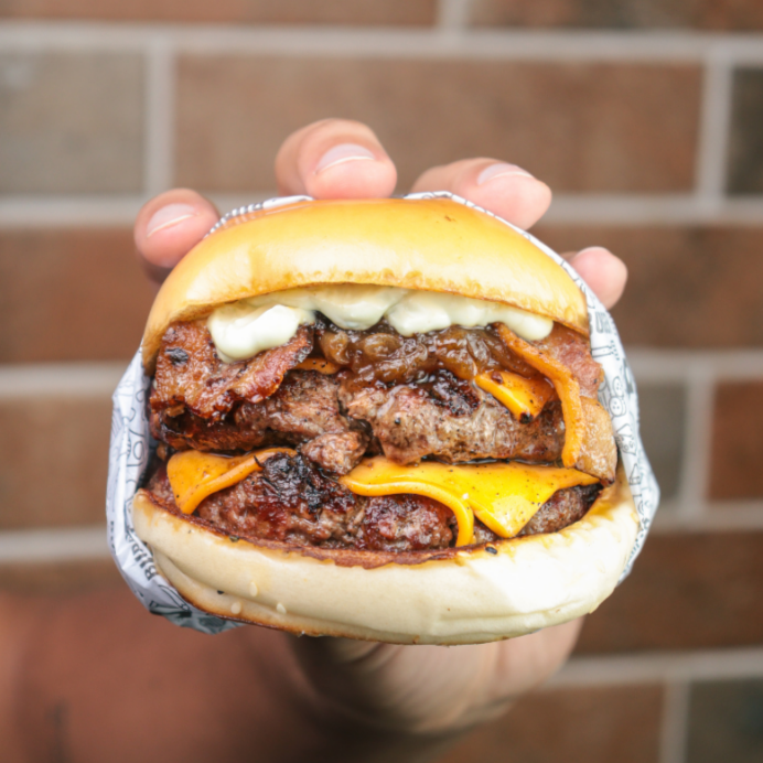 Pão brioche selado na manteiga, com 2 suculento blend bovino de 180g, bacon, cebola caramelizada, queijo cheddar derretido, e molho da casa.